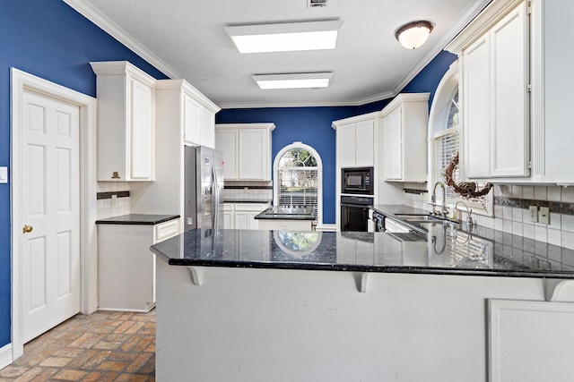 kitchen featuring backsplash, black appliances, white cabinets, sink, and kitchen peninsula