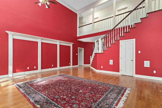 entryway with wood-type flooring, a towering ceiling, and ceiling fan