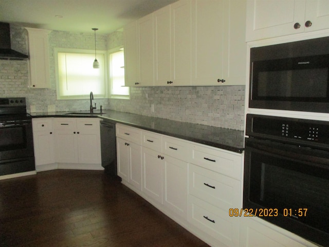 kitchen featuring sink, wall chimney exhaust hood, decorative light fixtures, white cabinets, and black appliances