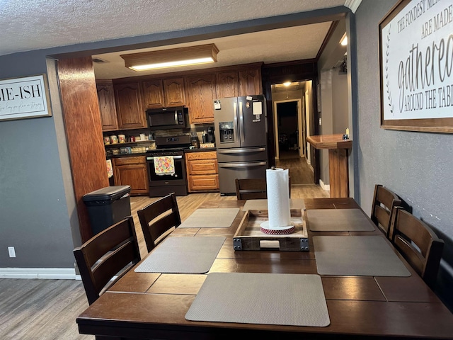 6358 Nick Ave, Port Arthur, TX 77640 - kitchen with stove, stainless steel refrigerator with ice dispenser, black microwave, a textured ceiling, and light wood-style floors