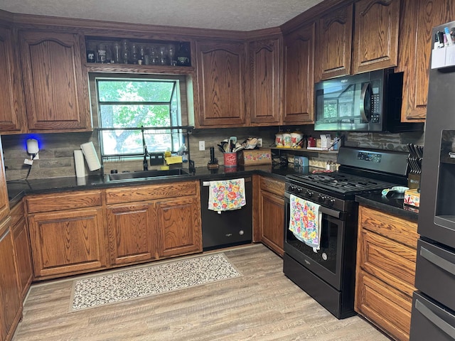6358 Nick Ave, Port Arthur, TX 77640 - kitchen with black appliances, a sink, dark countertops, light wood-style floors, and decorative backsplash