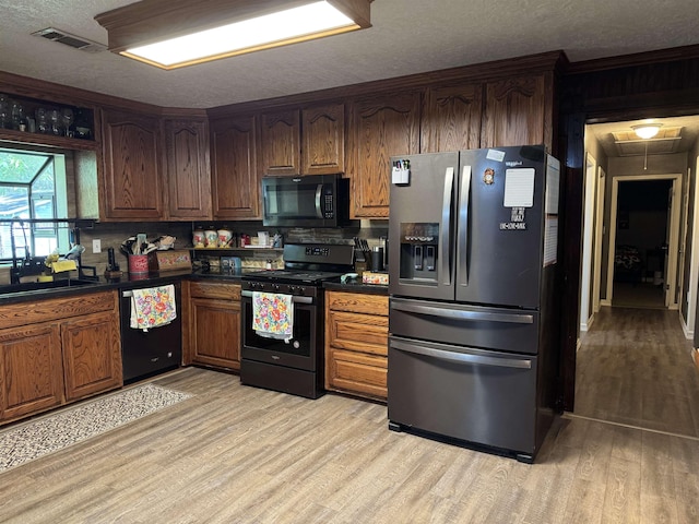 6358 Nick Ave, Port Arthur, TX 77640 - kitchen featuring black appliances, light wood finished floors, dark countertops, a textured ceiling, and a sink