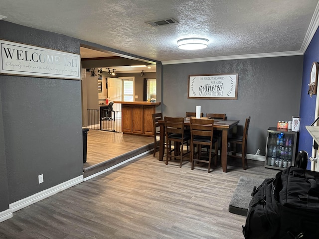 6358 Nick Ave, Port Arthur, TX 77640 - dining space with wood finished floors, a textured wall, ornamental molding, a textured ceiling, and baseboards