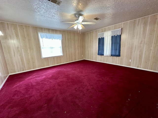 carpeted empty room with baseboards, ceiling fan, visible vents, and a textured ceiling