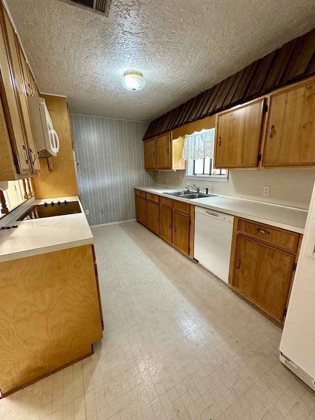 kitchen with light floors, white appliances, brown cabinetry, and a sink