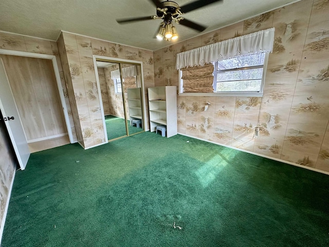 unfurnished bedroom featuring a textured ceiling, carpet, a ceiling fan, and wallpapered walls