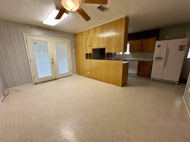 kitchen with french doors, brown cabinets, light floors, visible vents, and white appliances