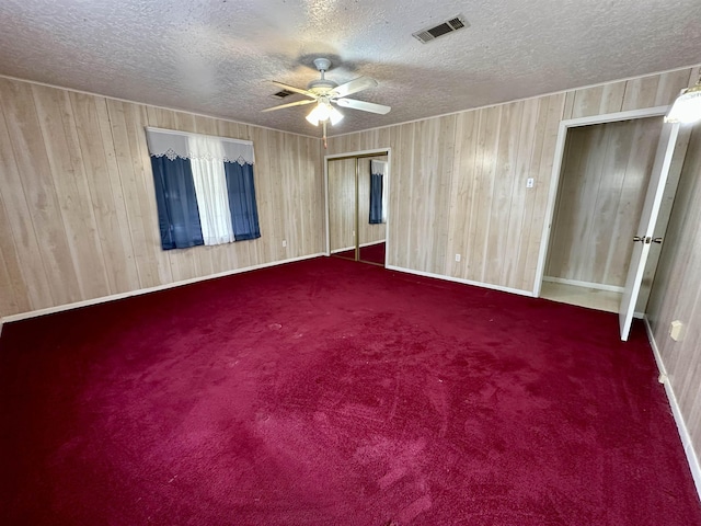 unfurnished room with a textured ceiling, carpet flooring, visible vents, and a ceiling fan