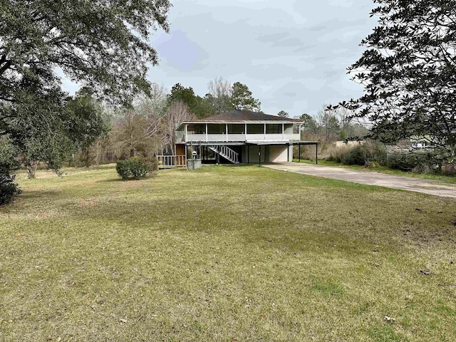 view of front facade featuring a carport, stairs, a front lawn, and concrete driveway