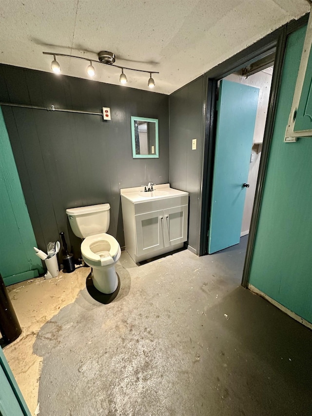 bathroom with unfinished concrete flooring, vanity, toilet, and a textured ceiling