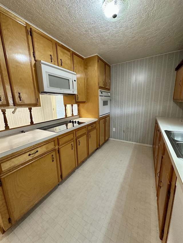 kitchen with a textured ceiling, white appliances, light countertops, brown cabinets, and light floors