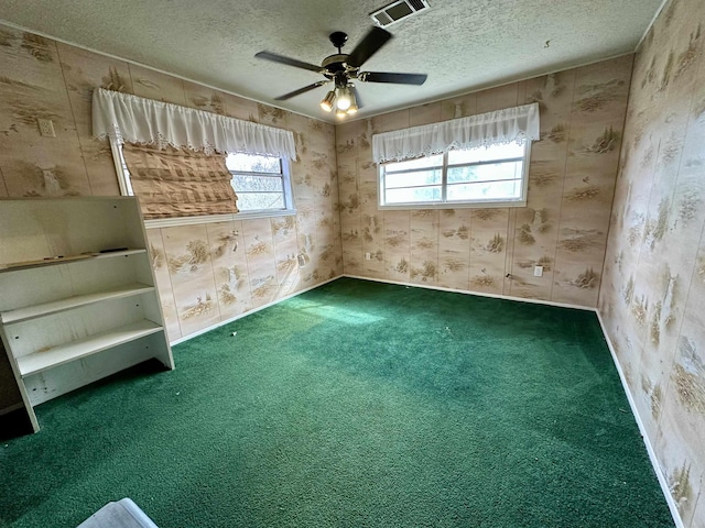 empty room with a textured ceiling, visible vents, a ceiling fan, carpet, and wallpapered walls