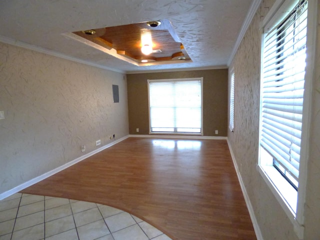 unfurnished room featuring a raised ceiling, crown molding, and light tile patterned flooring