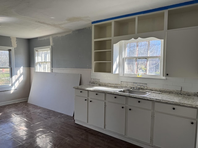 kitchen with open shelves, a sink, white cabinetry, light countertops, and decorative backsplash