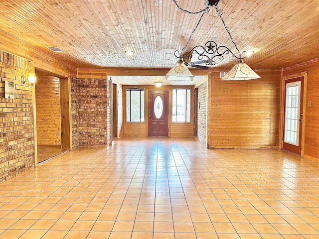 foyer entrance featuring light tile patterned floors, wood walls, visible vents, wooden ceiling, and brick wall