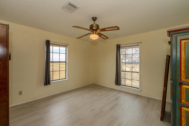 empty room featuring ceiling fan, a textured ceiling, and light hardwood / wood-style flooring