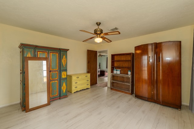 interior space with ceiling fan, light wood-type flooring, and a textured ceiling