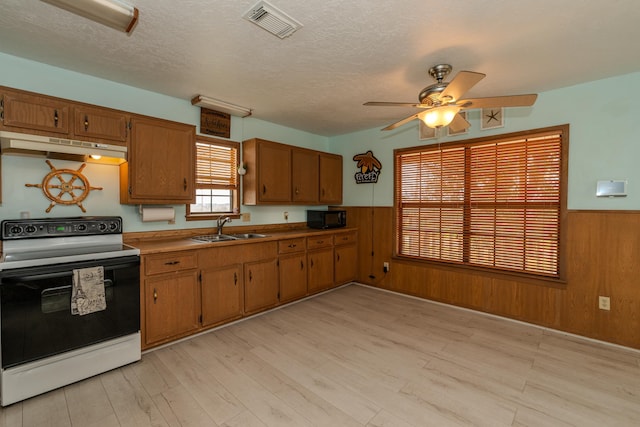 kitchen with ceiling fan, sink, white electric range, wood walls, and a textured ceiling