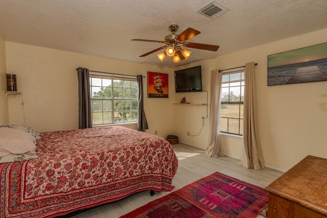 bedroom featuring light wood-type flooring, a textured ceiling, and ceiling fan