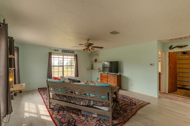 bedroom with ceiling fan, light hardwood / wood-style floors, and a textured ceiling