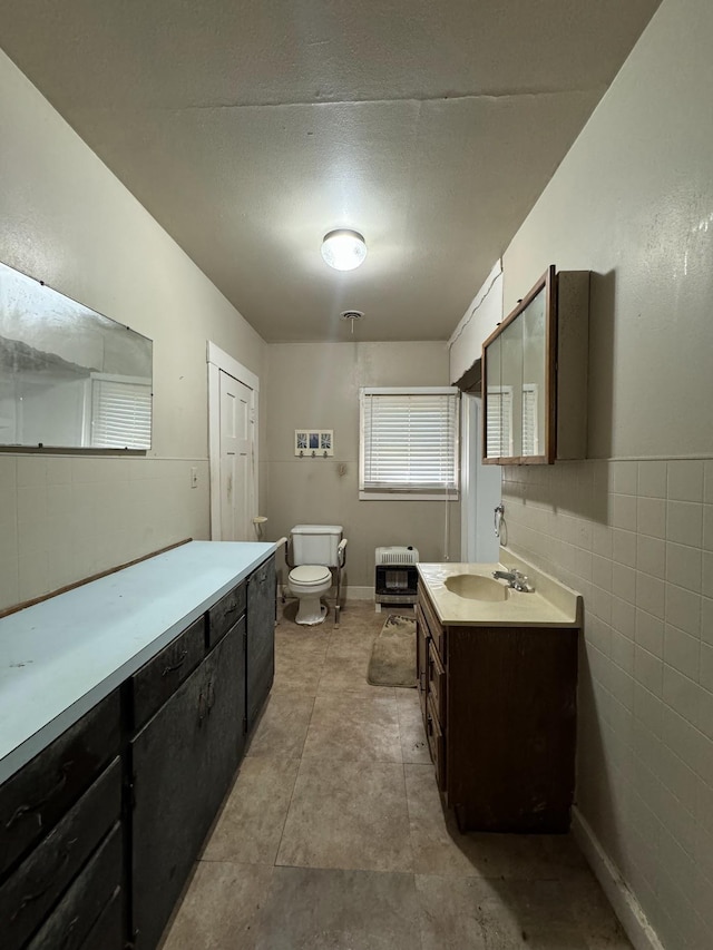 bathroom featuring heating unit, vanity, and toilet