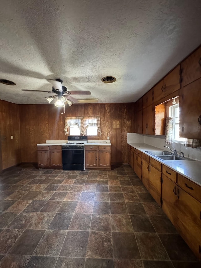 kitchen featuring wood walls, white gas range, sink, and a wealth of natural light