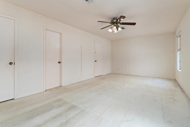 unfurnished bedroom featuring carpet flooring, ceiling fan, multiple closets, and visible vents