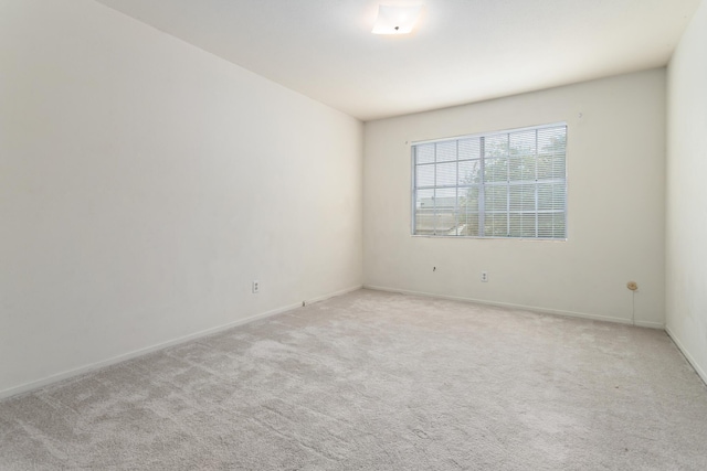 unfurnished room featuring baseboards and light colored carpet