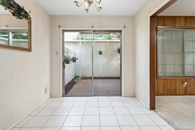 doorway featuring baseboards and a chandelier
