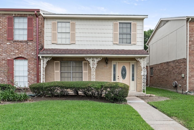 view of front of home featuring brick siding, roof with shingles, and a front yard