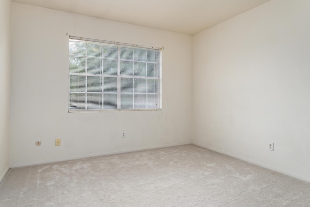 unfurnished room featuring baseboards and light carpet