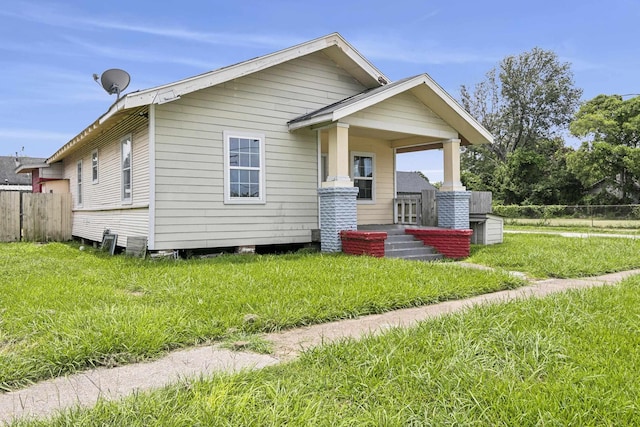 bungalow featuring covered porch, a front yard, and fence