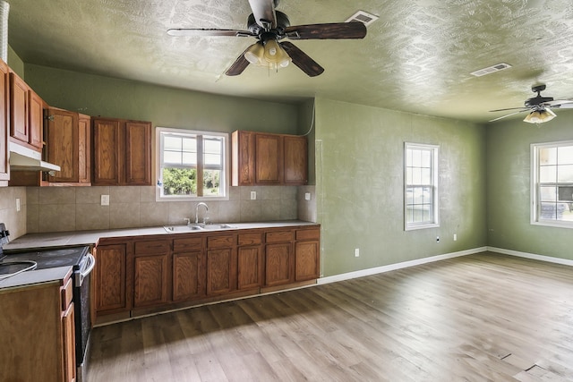 kitchen with a textured ceiling, a sink, range with electric stovetop, ceiling fan, and under cabinet range hood
