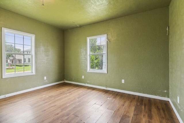 unfurnished room featuring hardwood / wood-style floors, plenty of natural light, and baseboards
