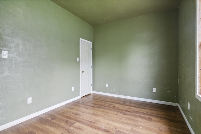 spare room with baseboards and wood finished floors