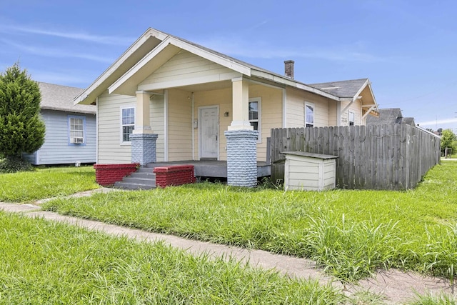 bungalow-style home featuring a chimney, fence, and a porch