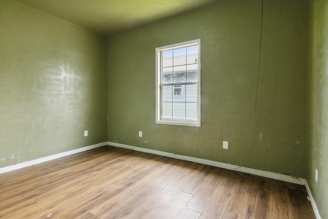 spare room with baseboards and wood finished floors