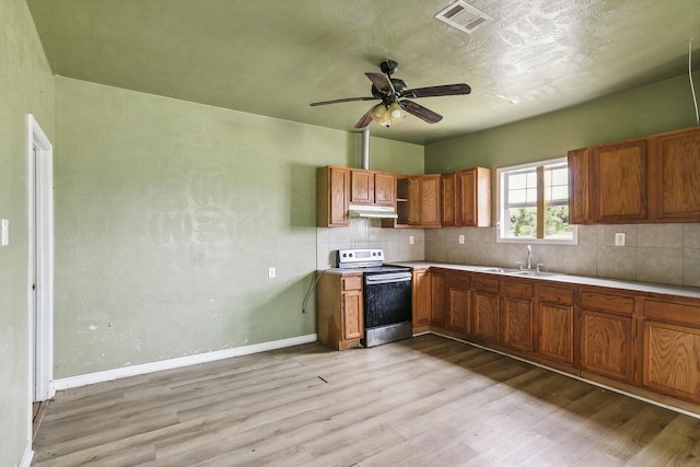 kitchen with under cabinet range hood, visible vents, a sink, light wood-type flooring, and electric range