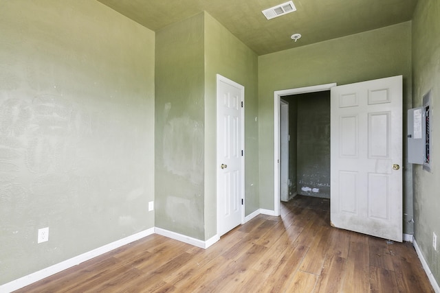 unfurnished bedroom featuring wood finished floors, visible vents, electric panel, and baseboards