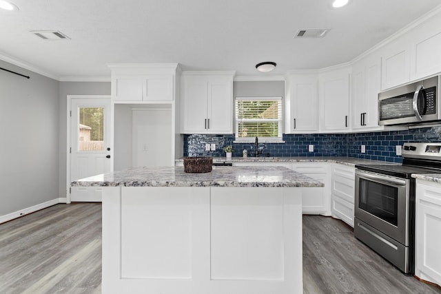 125 Needles, Vidor, TX 77662 - kitchen with appliances with stainless steel finishes, tasteful backsplash, a center island, wood finished floors, and crown molding