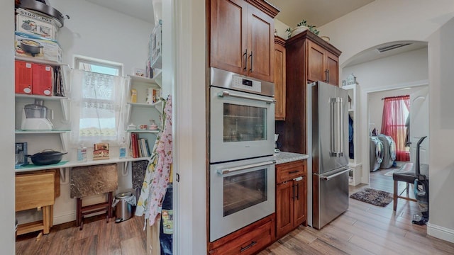 15360 Hercules Dr, Beaumont, TX 77713 - kitchen featuring stainless steel appliances, light wood-style flooring, washer and dryer, and arched walkways