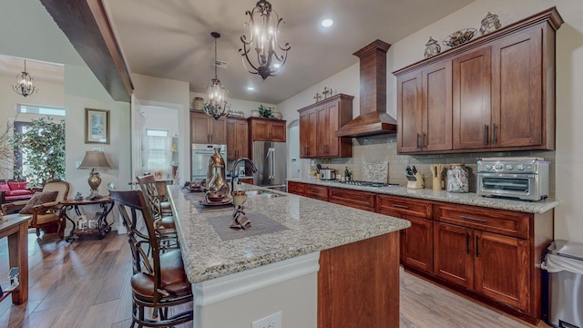 15360 Hercules Dr, Beaumont, TX 77713 - kitchen featuring a chandelier, wall chimney exhaust hood, light wood-style floors, appliances with stainless steel finishes, and recessed lighting