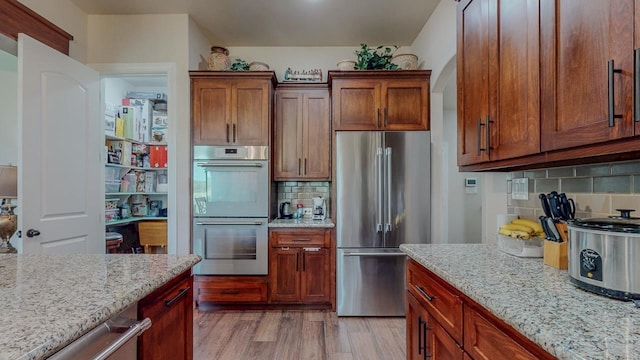 15360 Hercules Dr, Beaumont, TX 77713 - kitchen featuring stainless steel appliances, light stone counters, tasteful backsplash, and light wood-style floors