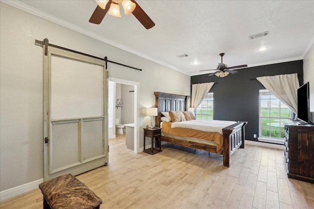 bedroom featuring crown molding, ceiling fan, connected bathroom, light hardwood / wood-style floors, and a barn door