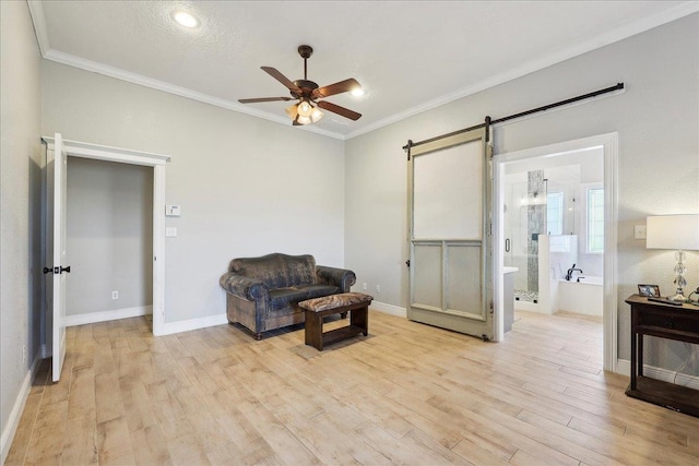 living area with ceiling fan, ornamental molding, a barn door, and light hardwood / wood-style flooring