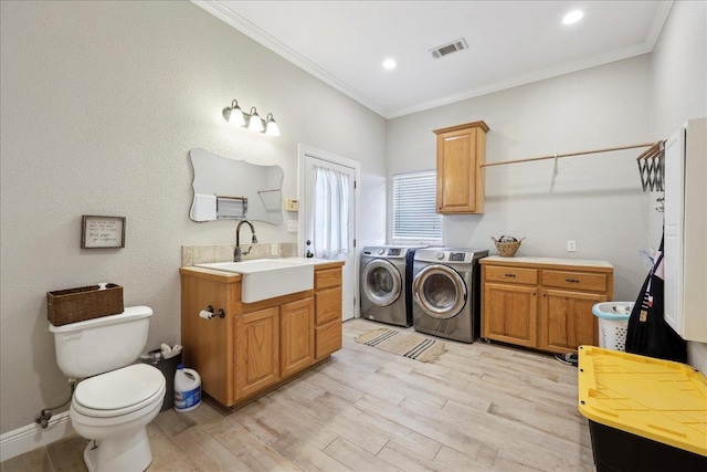 clothes washing area featuring crown molding, independent washer and dryer, sink, and light hardwood / wood-style flooring