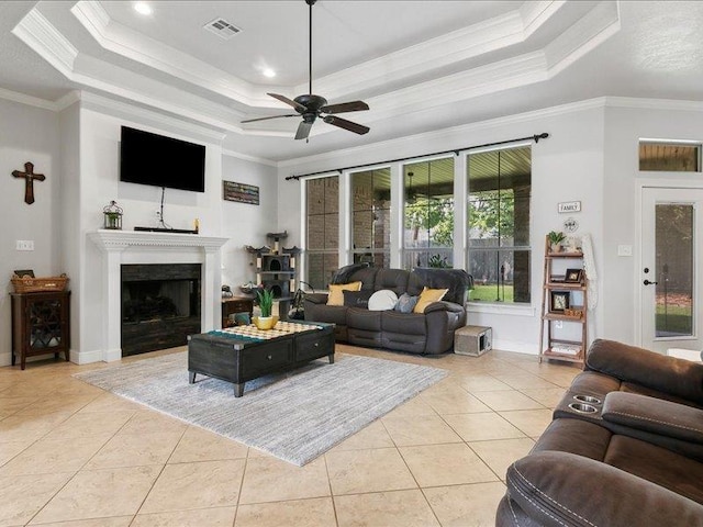 tiled living room featuring a raised ceiling, ceiling fan, and ornamental molding