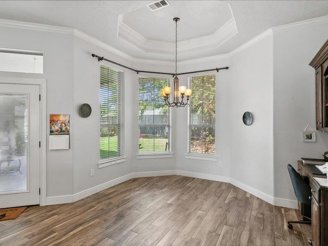 unfurnished dining area with a raised ceiling, crown molding, a notable chandelier, and hardwood / wood-style flooring