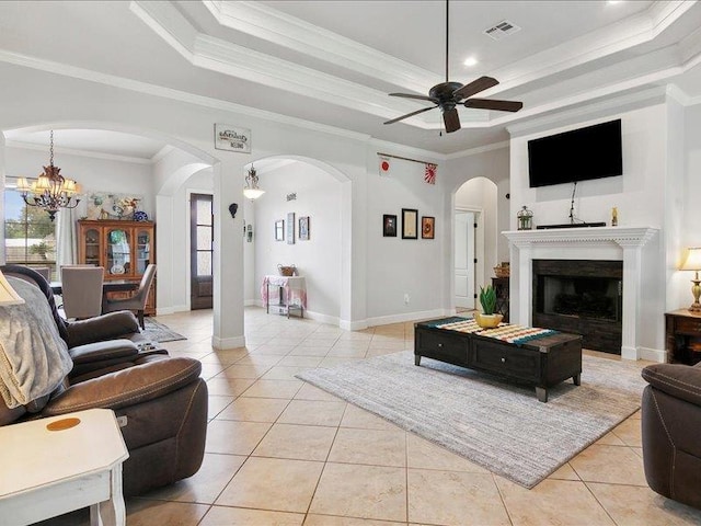 tiled living room featuring ceiling fan with notable chandelier, ornamental molding, and a tray ceiling