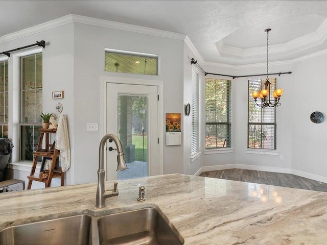 kitchen with sink, a raised ceiling, a chandelier, decorative light fixtures, and ornamental molding